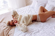 © zinkevych - Woman wearing white lace panties and beige sweater lying in bed
