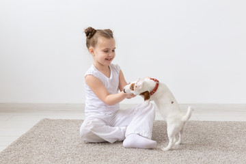 Dogs, children and pets concept - little child girl sitting on the floor with cute puppy