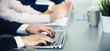© rogerphoto - Group of business people working together in office. Man hands typing on laptop computer