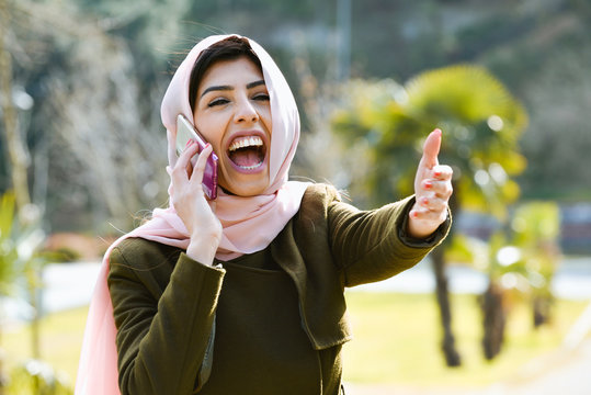 Beautiful young Muslim woman talking by phone