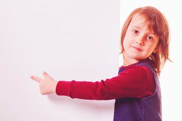 Llittle cute child girl pointing with her finger towards copy space area. Free space for text.