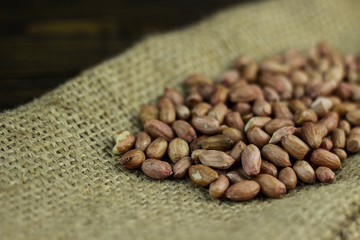 Wall Mural - Raw peanuts on a rough cloth and wooden background