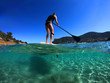 © aerial-drone - Underwater sea level photo of unidentified man on a SUP or Stand Up Paddle in turquoise crystal clear exotic mediterranean sandy beach