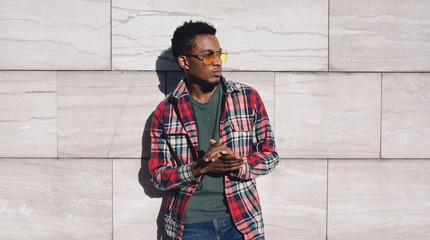 Wall Mural - Portrait stylish african man wearing red plaid shirt, looking away, guy posing on city street, gray brick wall background