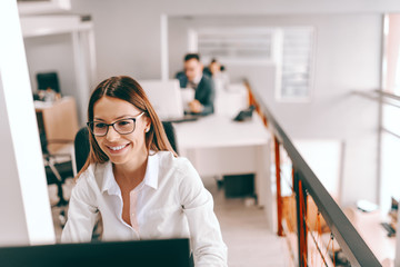 Cheerful Caucasian businesswoman in formal wear and with eyeglasses using computer for work. We all have ideas, but only brave ones make it happen.