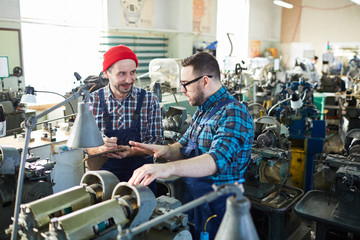 Portrait of mature factory worker training new employee during onboarding process, copy space