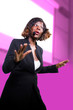 © TheVisualsYouNeed - confident black afro American business woman with microphone speaking in auditorium at corporate seminar event giving success coaching conference or political rally