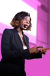 © TheVisualsYouNeed - young attractive and confident black African American business woman with microphone speaking in auditorium at corporate seminar event giving success coaching conference or political rally
