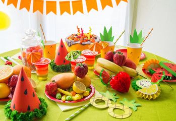 Decor for a holiday of children's birthday. Fruit party. Cake and sweet candy. Disposable tableware and tropical fruits.