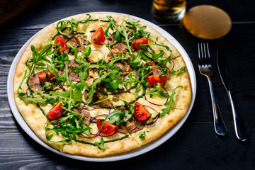 Wall Mural - Fresh arugula and tomato pizza on black table