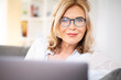 © Wellnhofer Designs - Frau mit Brille zuhause auf der Couch mit laptop