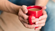 © golubovy - Coffee break. Relaxation and enjoyment time. Contemplation and warmth. Man hands around red cup of latte.