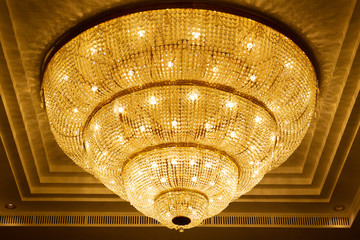 Wall Mural - Luxury crystal chandelier with yellow warm tone lighting close up. The luxury chandelier decorated in the public address.