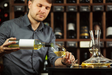 Wall Mural - Sommelier pouring white wine from bottle in glass