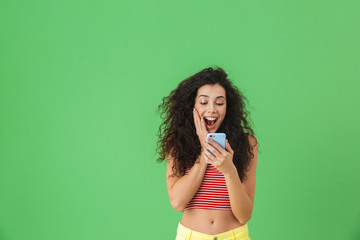 Canvas Print - Photo of gorgeous woman smiling and using cell phone isolated over green background