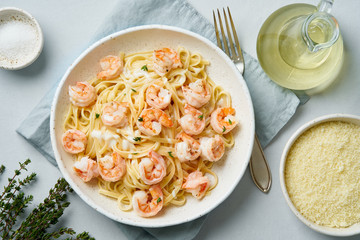 Wall Mural - Pasta bavette with fried shrimps, bechamel sauce, thyme on blue table, top view, italian cuisine.