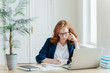 © VK Studio - Serious confident female entrepreneur in formal clothes writes down information while watches business webinar, notes main ideas, sits at work place in front of opened computer makes notes for startup
