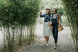 © PR Image Factory - full length asian women having fun together outdoors on hike through amazing bamboo forest trail. young girl pointing finger on tree showing sharing talking with friend. cheerful female tourist kyoto