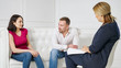 © lenblr - couple sitting on couch at psychologists, unhappy woman sharing marital problems talking to counselor holding clipboard. family marriage counseling therapy session concept