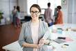 © Seventyfour - Waist up portrait of successful modern woman standing in office and smiling at camera, copy space