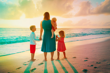 mother with kids looking at sunset on beach