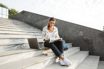 Sticker - Cheerful young teenage girl sitting on a staircase