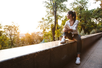 Poster - Lovely young student girl sitting outdoors