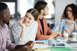 © Seventyfour - Portrait of smiling young woman talking to African-American colleague during meeting in office, copy space