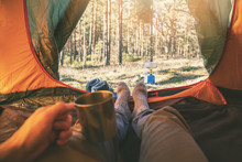 Outdoor Tourism - Man Laying In Tent With Cup Of Tea