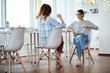 © Seventyfour - Full length portrait of two contemporary young women discussing work ideas sitting at table in office, copy space