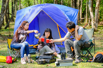 Asian teenager Coffee maker with red glass front of blue canvas camping tent on grass field with smile happy face