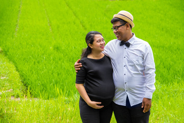 Pregnant woman and her husband smiling at each other. Maternity portrait in countryside nature