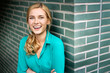 © Westend61 - Portrait of a cheerful young woman, leaning against wall with arms crossed