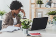 © lordn - Serious african-american business woman working on laptop at office