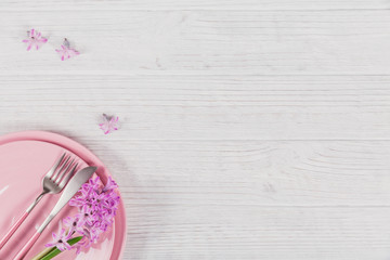 Pink rustic place setting with purple hyacinth flower and linen napkin on white wooden background