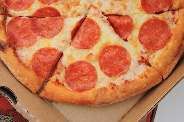 Pepperoni pizza slices isolated on wooden board close up view. Traditional classic hot italian pizza with pepperoni and cheese ingredients. Tasty fresh pepperoni pizza on plate for lunch