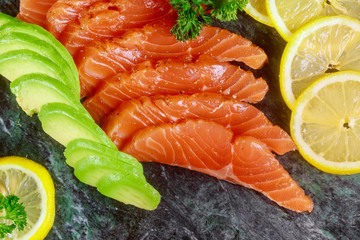 Wall Mural - Salmon sliced with lemon and avocado on marble plate