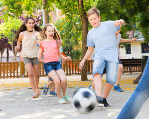 Wall Mural - Glad children  playfully running after ball