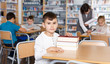 © JackF - Smiling boy sitting with pile of textbooks
