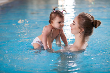 young mother bathes the baby in the pool.