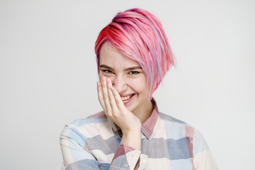 Young beautiful girl with a short hair cut pixie bob. Color hair coloring, red pink color. Shirt in a cellar, casual style.