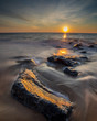 Sunset over the Atlantic as waves wash over rocks on the shore. Photo by: Chuck Beyer