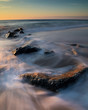 Ocean waves washing over rocks at the shore at sunrise. Photo by: Chuck Beyer