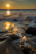 Waves crashing to shore at sunrise with the sun on the horizon reflecting off the water. Photo by: Chuck Beyer