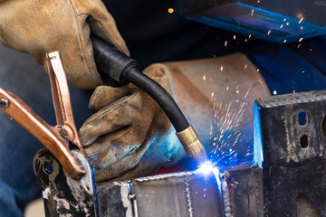 A mig welder is used to weld two pieces of metal steel together close up