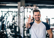 Smiling sportsman showing thumbs-up at the gym.
