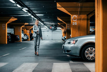 Successful businesswoman walking to her car in underground car parking.