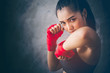 © brain2hands - Beautiful young Asian boxers. She is a martial arts athlete, strong face filled with sweat, her eyes are committed. Two of her hands with red boxing bandage hand wrap. Woman power with copy space.