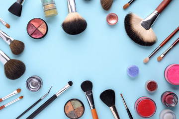 makeup brushes on a blue background. Top view, flat lay, copy space