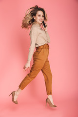 Poster - Full length portrait of pretty woman smiling and walking isolated over pink background